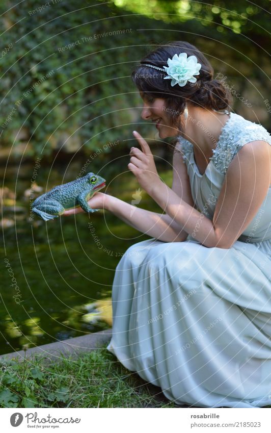 ... einen Frosch küssen ?          - junge brünette Frau im Abendkleid schaut einen Frosch an, den sie in der Hand hält feminin Junge Frau Prinzessin