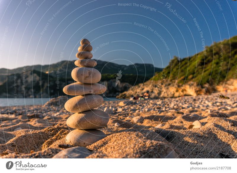 Steinpyramide auf einem Sandstrand mit Bergen und Wasser im Hintergrund Landschaft Wolkenloser Himmel Sommer Schönes Wetter Baum Sträucher Strand Bucht stehen