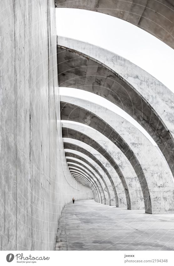 Modernes Sichtbeton Bauwerk, Mauer mit Bögen und Spaziergänger Hafenmauer Schutz Wellenbrecherdamm Architektur Breakwaters Beton Mann modern Bogen Schatten