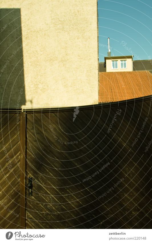 Hoftor Tür Tor Eingangstor Ausgang Haus geschlossen Exil Holztor Fassade Ecke Dach Dachfenster Textfreiraum unten Schatten Putz Blauer Himmel Menschenleer