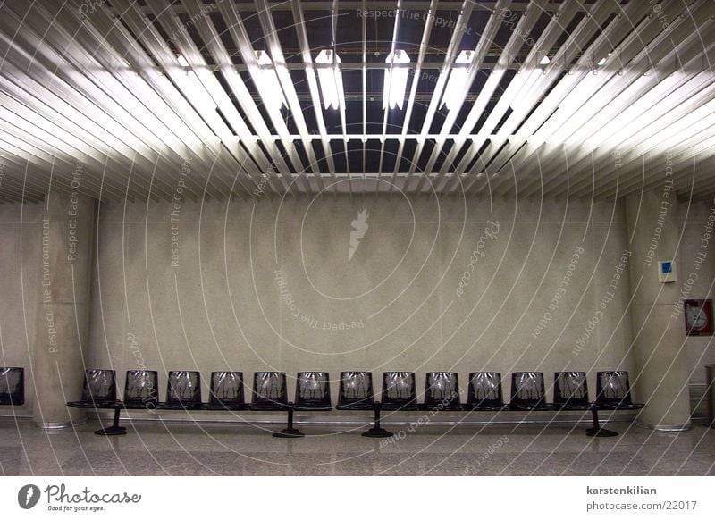 Unscheinbarer Wartesaal Licht Neonlicht grau Beton Stuhl Sitzreihe Warteraum Architektur Lagerhalle Säule Bank künstliches Licht leer