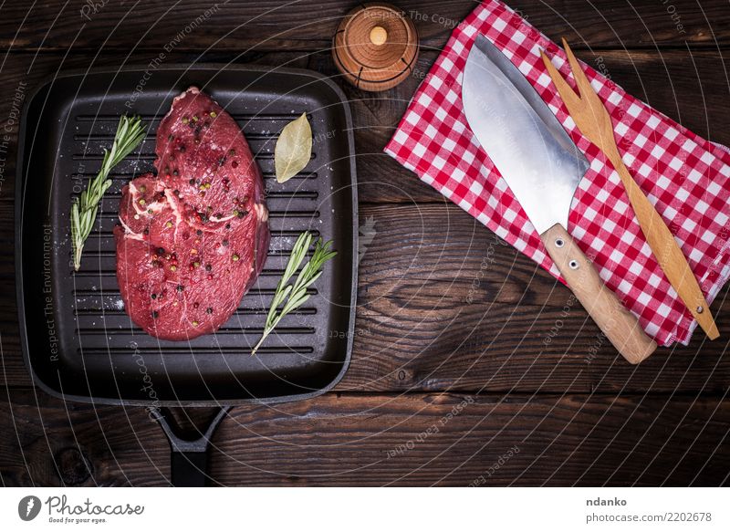 rohes Rindersteak mit Gewürzen Lebensmittel Fleisch Kräuter & Gewürze Abendessen Messer Gabel Tisch Küche Holz Essen frisch grün rot Bratpfanne Serviette