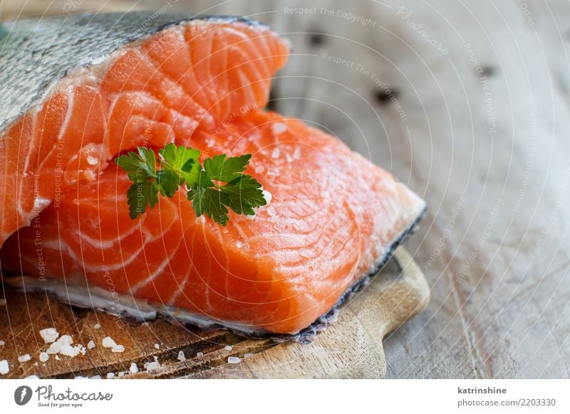 Frische rohe Lachse auf einem hölzernen Schneidebrett Fisch Meeresfrüchte Ernährung Essen Abendessen Diät Tisch frisch grün rot Hintergrund Holzplatte