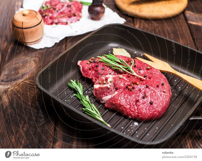 rohes Rindersteak in Gewürzen Fleisch Kräuter & Gewürze Abendessen Gabel Tisch Küche Kuh Papier Holz Essen frisch grün rot Hintergrund Rindfleisch Blut