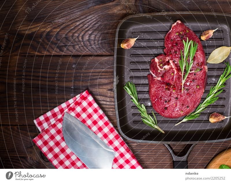 rohes Rindersteak in Gewürzen Fleisch Kräuter & Gewürze Abendessen Pfanne Messer Gabel Tisch Küche Papier Holz Essen frisch grün rot Mahlzeit Paprika