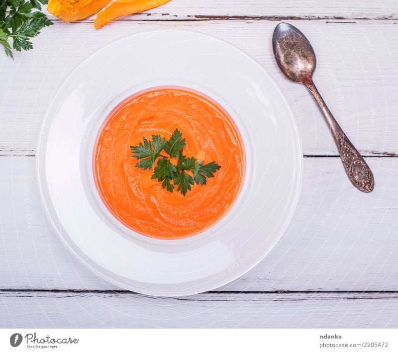 Teller mit Kürbiscremesuppe Gemüse Suppe Eintopf Essen Mittagessen Abendessen Vegetarische Ernährung Diät Löffel Tisch Herbst Holz frisch heiß oben gelb weiß