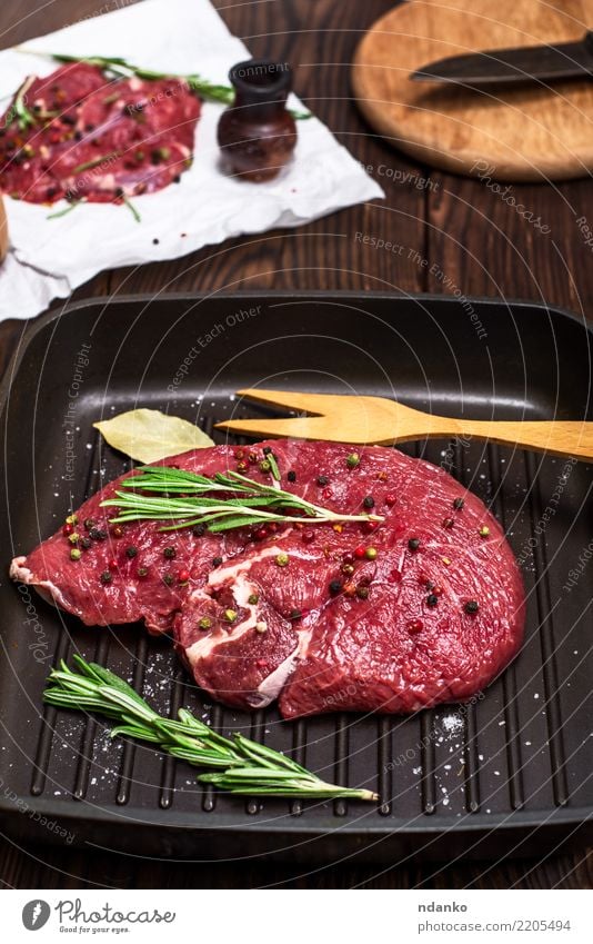 rohes Rindersteak Fleisch Kräuter & Gewürze Abendessen Pfanne Gabel Tisch Küche Papier Holz Essen frisch rot schwarz Hintergrund Rindfleisch Blut Holzplatte