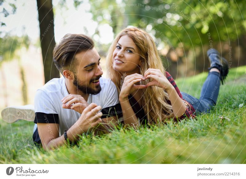 Schöne junge Paare, die auf Gras in einem städtischen Park legen. Lifestyle Freude Glück schön Sommer Mensch maskulin feminin Frau Erwachsene Mann 2 18-30 Jahre