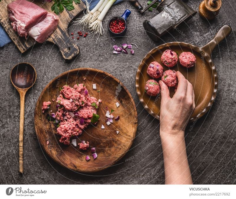 Hand legt Fleischbällchen in die Pfanne Lebensmittel Ernährung Mittagessen Abendessen Bioprodukte Teller Löffel Stil Design Häusliches Leben feminin Kochlöffel