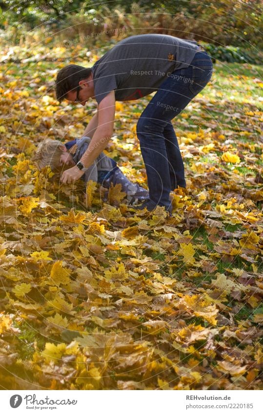 Mann spielt mit Kind im Herbstlaub Schwache Tiefenschärfe Unschärfe Sonnenlicht Tag Textfreiraum links Außenaufnahme Farbfoto Bewegung Lebensfreude