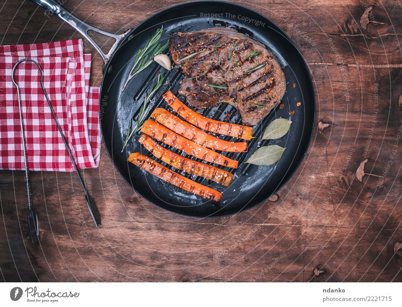 gebratener Rindfleischstapel Fleisch Gemüse Kräuter & Gewürze Mittagessen Pfanne Tisch Holz Essen heiß lecker braun rot schwarz Möhre Sesam Zange Serviette