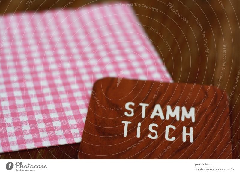 Bierdeckel mit Aufdruck Stammtisch auf karierter Serviette und Holztisch Tisch Dorf Schriftzeichen ästhetisch außergewöhnlich einzigartig Kitsch braun rosa