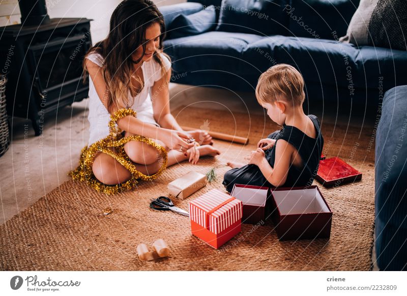 Junge Familie, die zu Hause Weihnachtsgeschenke einwickelt Freude Glück Winter Wohnzimmer Weihnachten & Advent Kindererziehung Handwerk Kleinkind Eltern