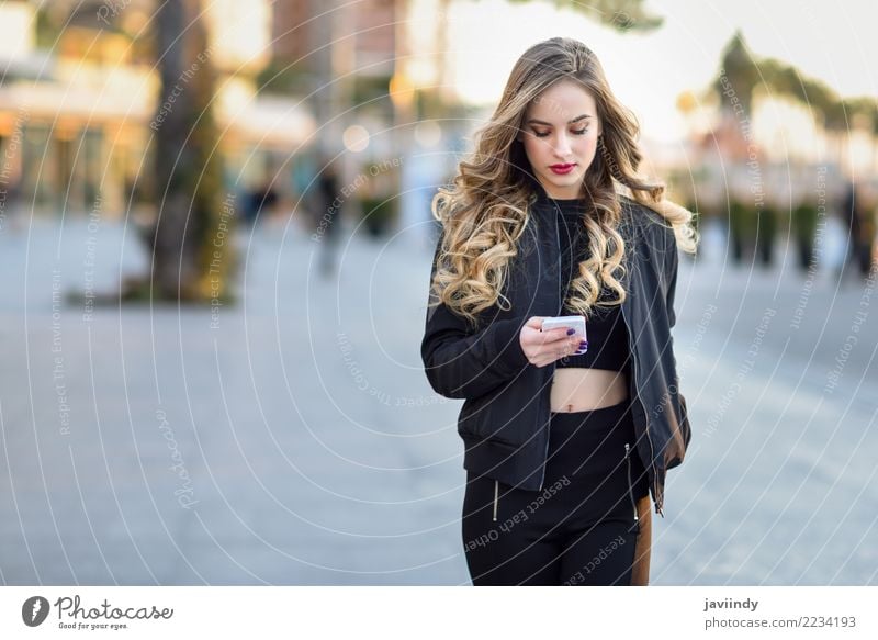 Frau, die mit ihrem intelligenten Telefon im städtischen Hintergrund simst Lifestyle Stil schön Haare & Frisuren PDA Mensch feminin Junge Frau Jugendliche