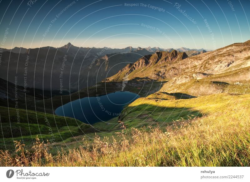 Sonnenaufgang über Alpengipfeln und See im Sommer Berge u. Gebirge Natur Landschaft Himmel Wolkenloser Himmel Sonnenlicht Schönes Wetter Felsen Gipfel blau