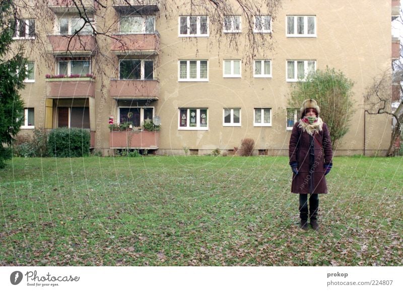 Frau vor Haus Mensch Junge Frau Jugendliche Erwachsene Wiese Fassade Balkon Fenster Bekleidung Hose Mantel Fell Schal Handschuhe Stiefel Mütze stehen warten