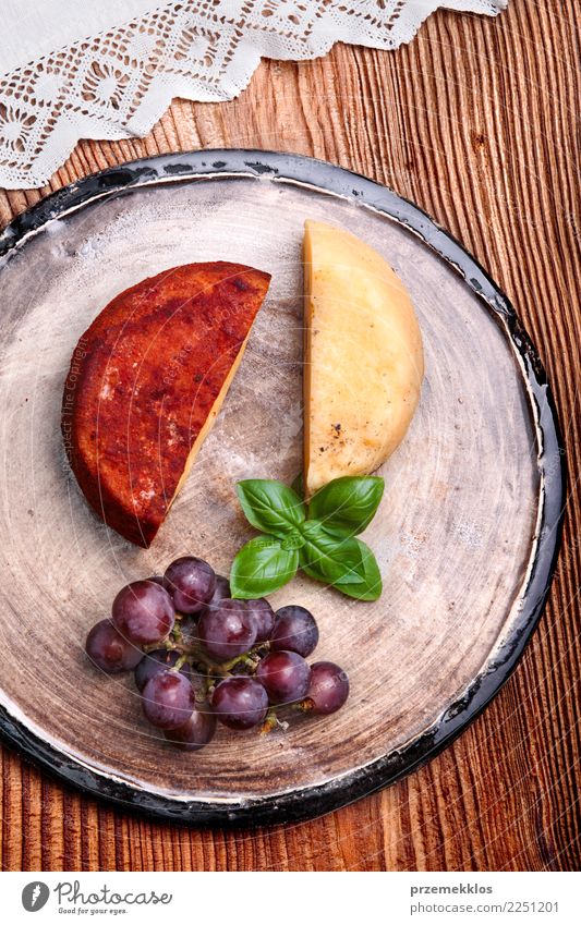 Käse und schwarze Trauben auf handgemachter Tonwarenplatte Lebensmittel Frucht Ernährung Frühstück Teller Tisch Holz Rost frisch lecker oben Keramik