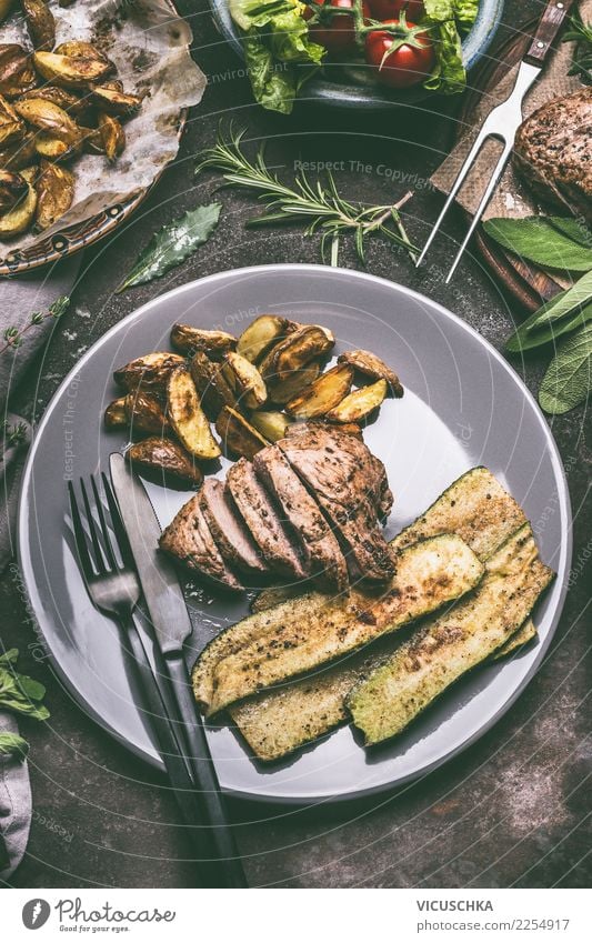 Essen mit gebratenem Fleisch, Bratkartoffeln und Gemüse Lebensmittel Ernährung Mittagessen Abendessen Bioprodukte Geschirr Teller Besteck Stil Design Restaurant