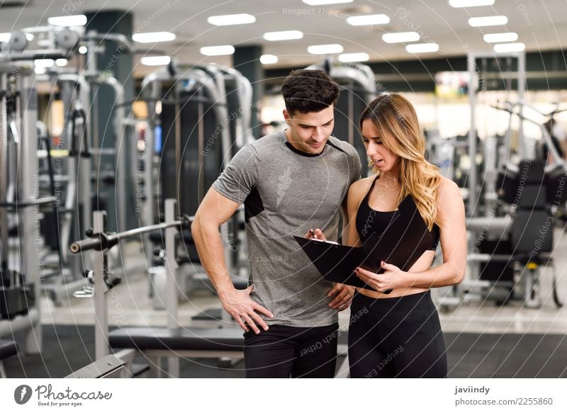 Persönlicher Trainer und Kunde, die seinen Fortschritt an der Turnhalle betrachten Lifestyle Körper Wellness Sport Mensch maskulin feminin Junge Frau