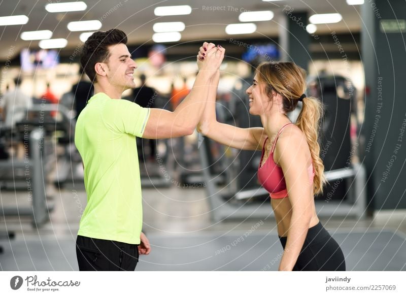 Lächelnder junger Mann und Frau, die Hoch fünf in der Turnhalle tun Lifestyle Glück Körper Wellness Feste & Feiern Sport Erfolg Mensch maskulin feminin