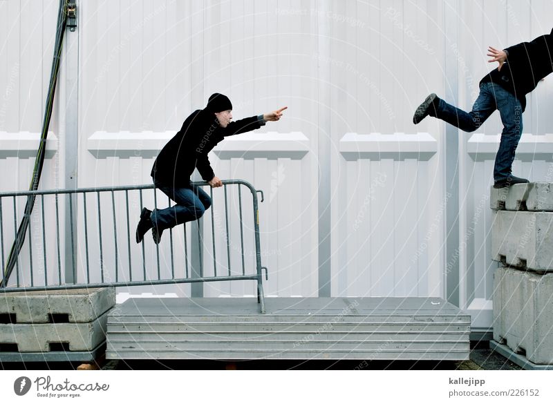 jemanden auf diesem foto markieren maskulin Mann Erwachsene 2 Mensch 30-45 Jahre Mauer Wand Jeanshose Mantel Schuhe Mütze sitzen zeigen Zeigefinger Richtung