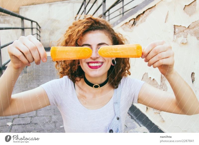 Junge glückliche Frau, die zwei orange Eiscreme anhält Lebensmittel Dessert Speiseeis Lifestyle Stil Freude schön Ferien & Urlaub & Reisen Sommer Sommerurlaub