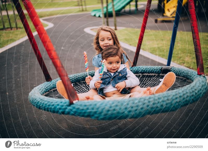 Nette junge sublings, die zusammen auf Schwingen sitzen Freude Glück Spielen Kleinkind Schwester Familie & Verwandtschaft Park Spielplatz Lächeln Umarmen