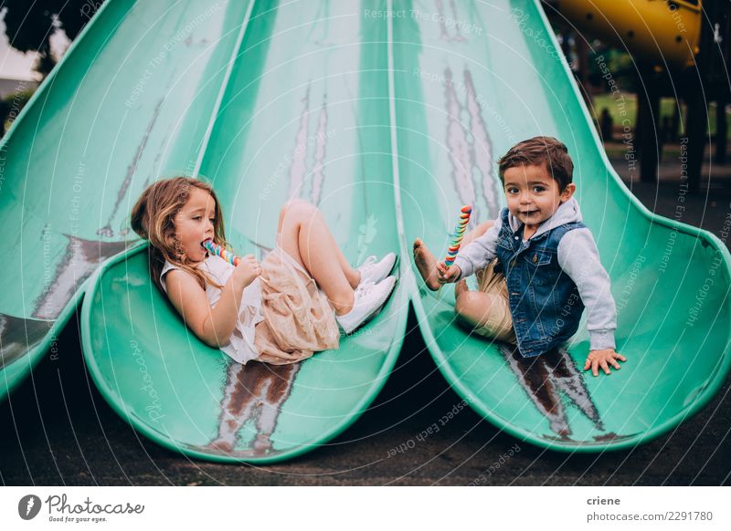 Nette kaukasische Geschwister, die auf Dia auf Spielplatz sitzen Essen Freude Glück Junge Schwester Familie & Verwandtschaft Kindheit Lächeln niedlich Bruder