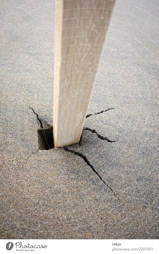 Unlackierter Pfahl steckt im nassen Sandboden mit Riß. Strand Holzpfahl kaputt Riss Pfosten roh stecken beweglich losgelöst wackelig Stabilität Boden Farbfoto