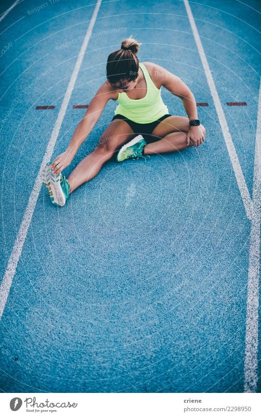 Junger weiblicher Athlet, der auf blaue Laufbahn ausdehnt Lifestyle Sport Leichtathletik Erfolg Joggen Stadion Rennbahn Mensch Frau Erwachsene Konkurrenz