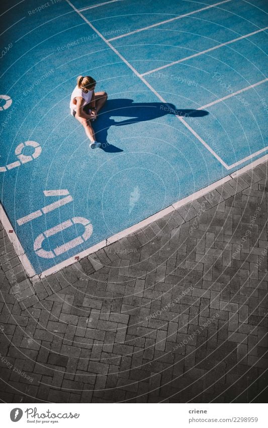 Geeignete athletische Frau, die nach hartem Training auf Laufbahn stillsteht Lifestyle Sport Leichtathletik Erfolg Stadion Mensch Erwachsene Schuhe Fitness blau