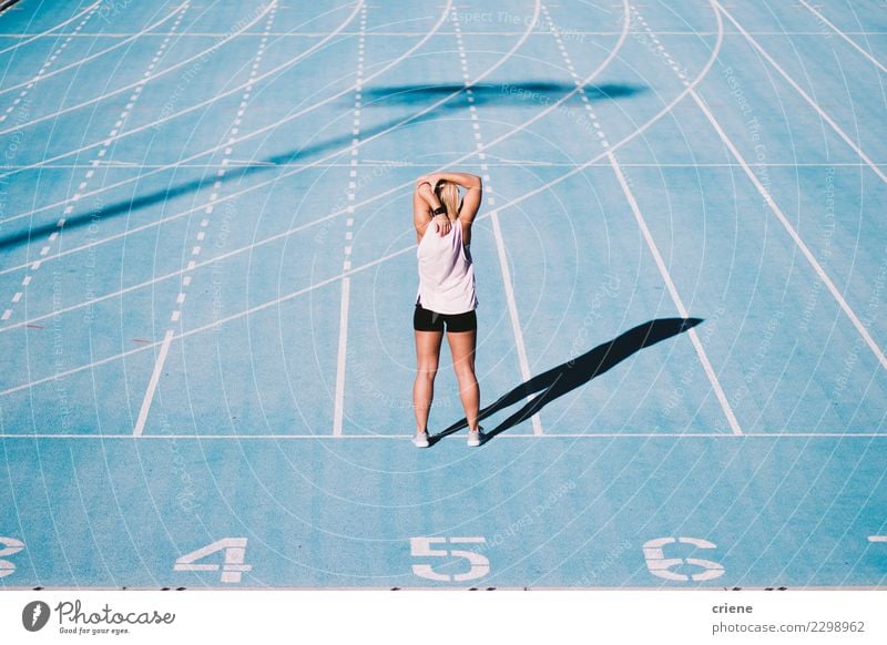 Kaukasischer junger Erwachsener, der vorher Arme auf Laufbahn ausdehnt Lifestyle Sport Leichtathletik Erfolg Stadion Mensch Frau Schuhe Fitness blau Beginn