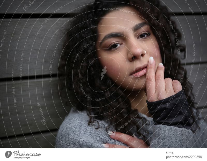 Nikolija feminin Frau Erwachsene 1 Mensch Mauer Wand Pullover brünett langhaarig Locken beobachten Denken festhalten Blick dunkel schön selbstbewußt Coolness