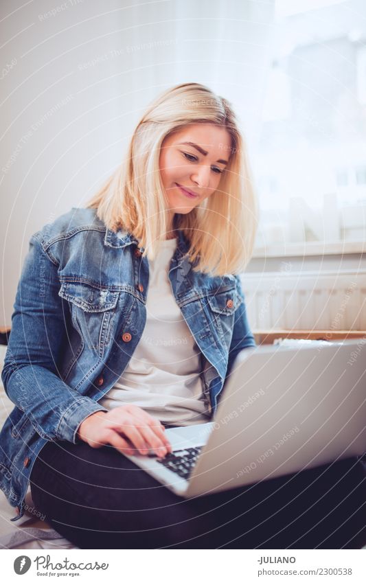 Junge Frau, die auf der Couch sitzt und mit dem Notebook arbeitet. Lifestyle kaufen Häusliches Leben Wohnung Innenarchitektur Raum Wohnzimmer Mensch feminin