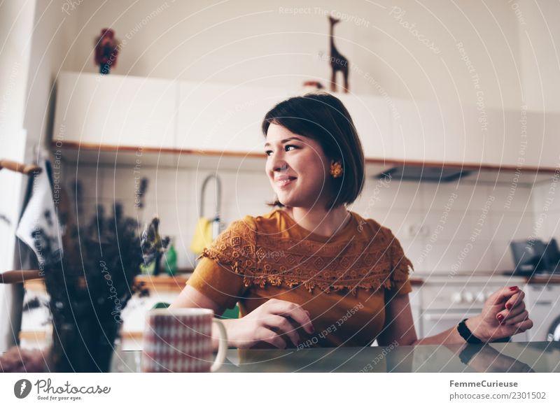 Young woman sitting at a kitchen table feminin Junge Frau Jugendliche Erwachsene 1 Mensch 18-30 Jahre Häusliches Leben Küche Küchentisch Gute Laune Vorfreude