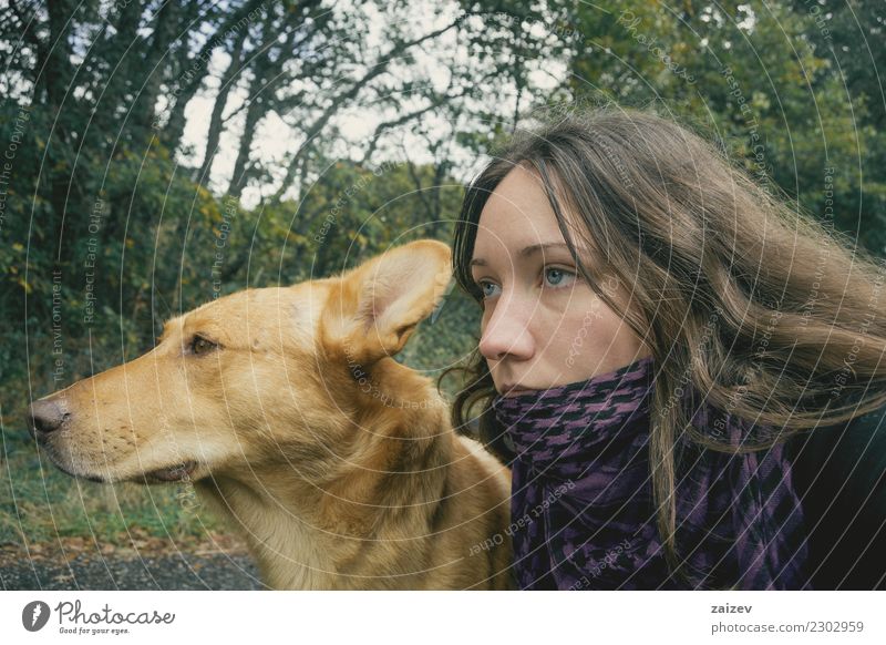 Perro de color marron claro junto a chica de ojos azules y cabello largo mirando juntos hacia adelante, esperando. Lifestyle schön Wellness Erholung wandern