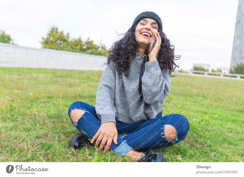 Frau, die um das Telefon sitzt auf dem Gras und dem Lächeln ersucht Lifestyle elegant Handy PDA Technik & Technologie Internet Erwachsene Jugendliche