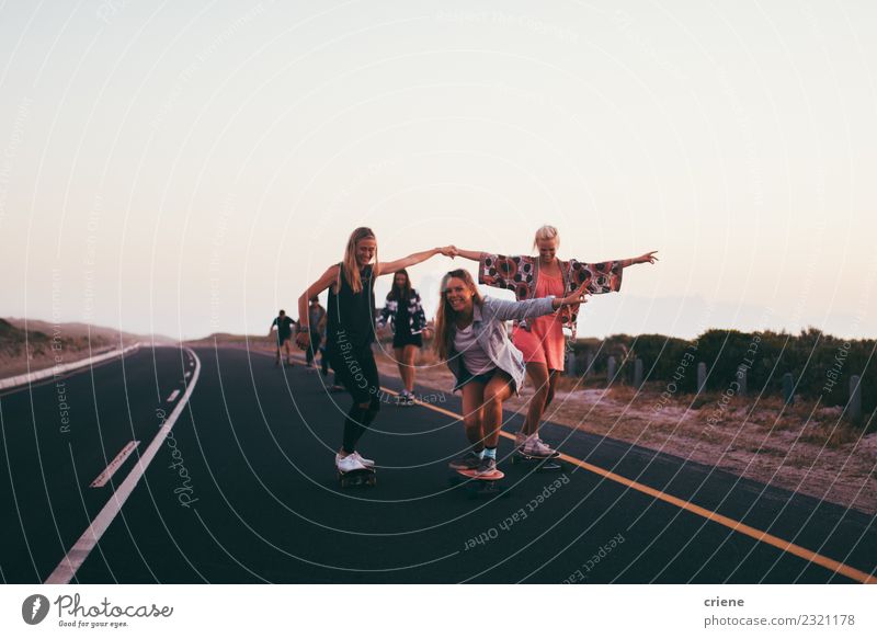 Junge erwachsene Gruppe von Freunden, die zusammen Longboards auf der Straße fahren. Lifestyle Freude Glück Freizeit & Hobby Abenteuer Freiheit Sport