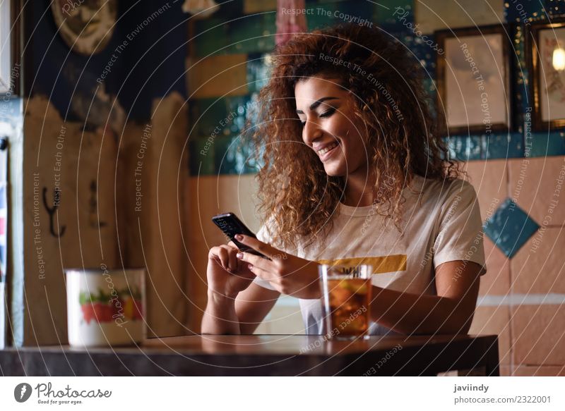 Frau in einer schönen Bar, die auf ihr Smartphone schaut. Getränk trinken Lifestyle Stil Freude Glück Haare & Frisuren Freizeit & Hobby Restaurant Telefon