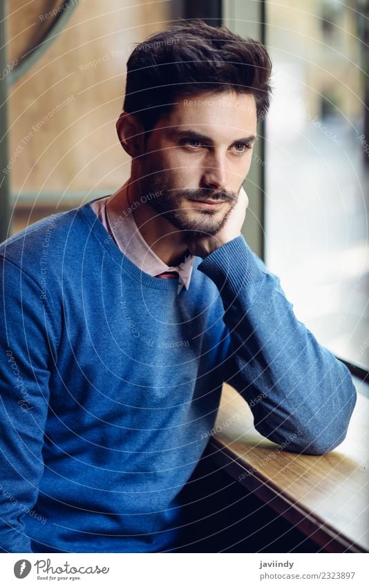 Nachdenklicher Mann mit verlorenem Blick in der Nähe eines Fensters in einem modernen Pub. Lifestyle Stil schön Haare & Frisuren Mensch maskulin Junger Mann