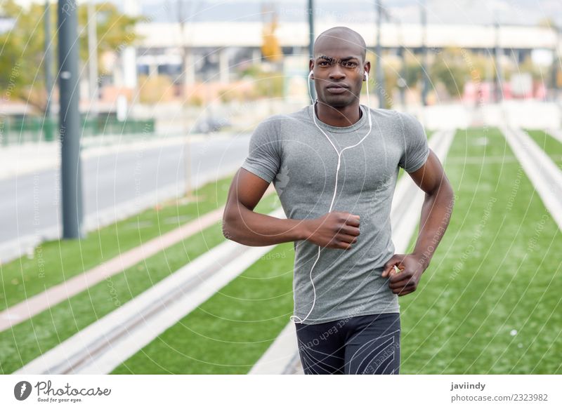 Schwarzer Mann, der im urbanen Hintergrund läuft und Musik hört. Lifestyle Körper Sport Joggen Headset Mensch maskulin Junger Mann Jugendliche Erwachsene 1