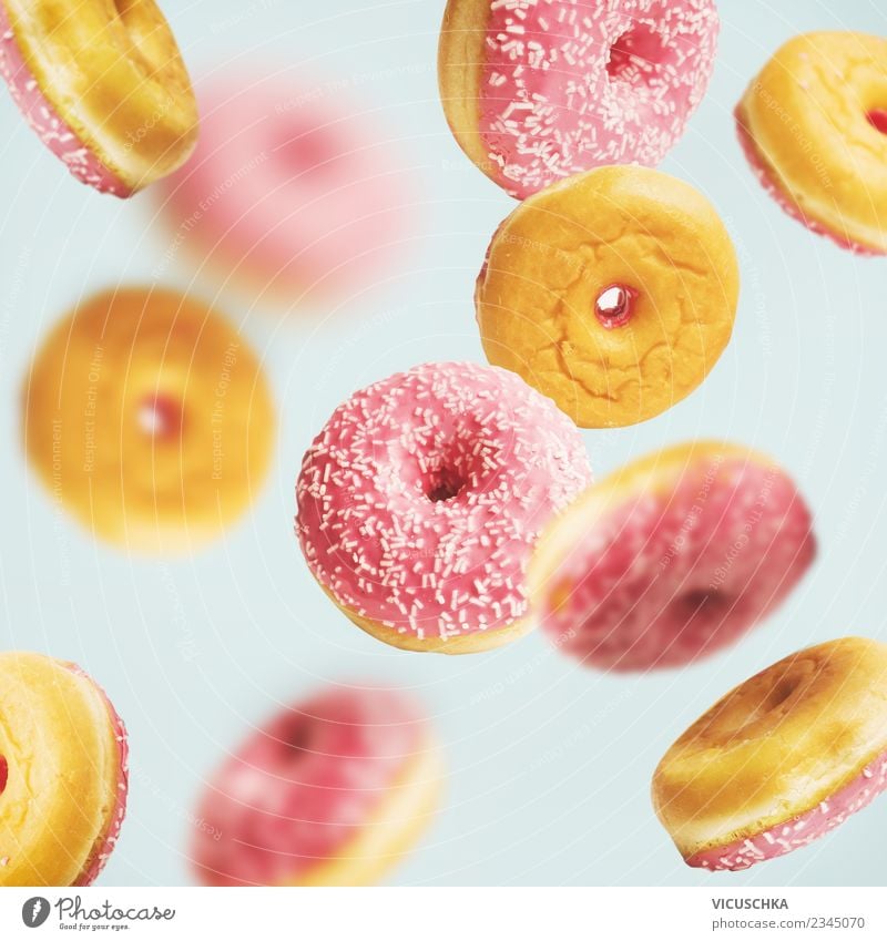 Fallende oder fliegende rosa glasierte Doughnuts Lebensmittel Kuchen Dessert Süßwaren Ernährung Stil Design trendy blau gelb türkis Krapfen fallen