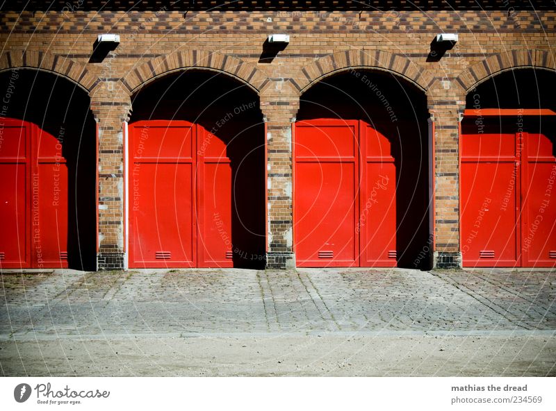 TATÜ TATA Menschenleer Haus Bauwerk Architektur Mauer Wand Fassade Tür rot Feuerwehr Tor Symmetrie Backstein Muster schön Bürgersteig ruhig Lampe Wasser löschen