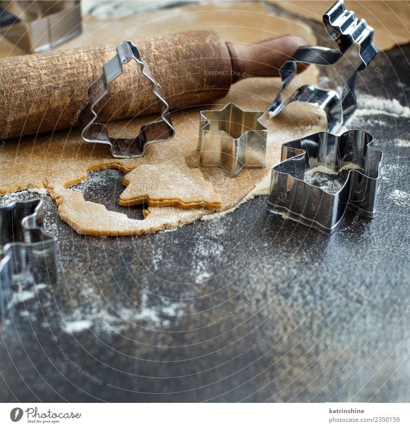 Weihnachtskekse mit Keksausstechern auf einem dunklen Tisch zubereiten. Teigwaren Backwaren Dessert Winter Küche Metall machen braun weiß Tradition backen