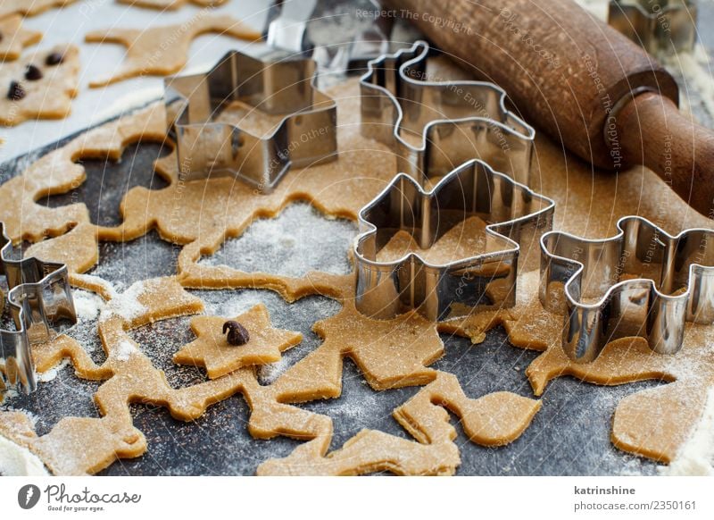 Weihnachtskekse mit Keksausstechern auf einem dunklen Tisch zubereiten. Teigwaren Backwaren Dessert Winter Küche Metall machen braun weiß Tradition backen