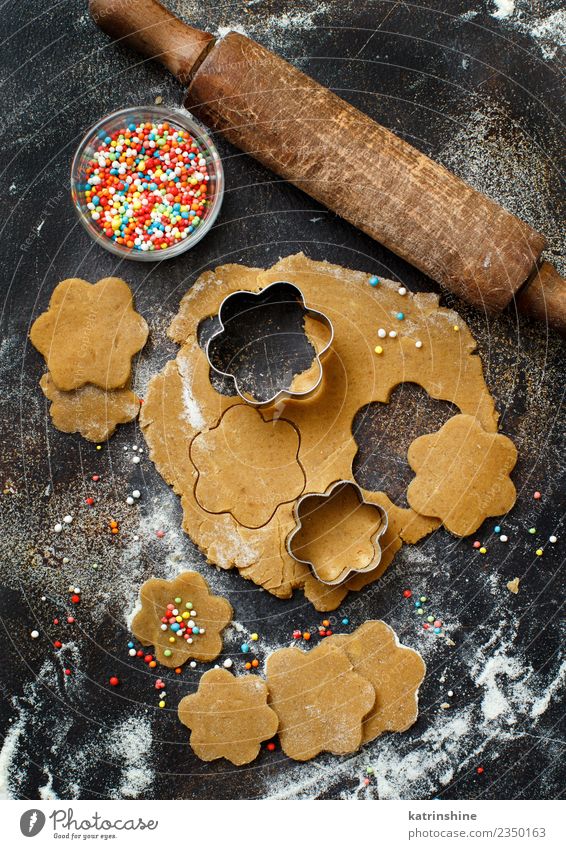 Kekse mit Keksausstechern auf einem dunklen Tisch zubereiten. Teigwaren Backwaren Dessert Küche Blume Metall machen oben braun Tradition backen Bäckerei Biskuit