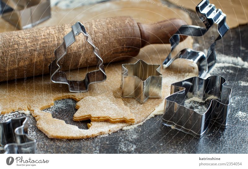 Weihnachtskekse mit Keksausstechern auf einem dunklen Tisch zubereiten. Teigwaren Backwaren Dessert Winter Küche Metall Engel machen braun weiß Tradition backen