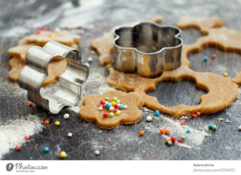 Kekse mit Keksausstechern auf einem dunklen Tisch zubereiten. Teigwaren Backwaren Dessert Küche Blume Metall machen braun Tradition backen Bäckerei Biskuit