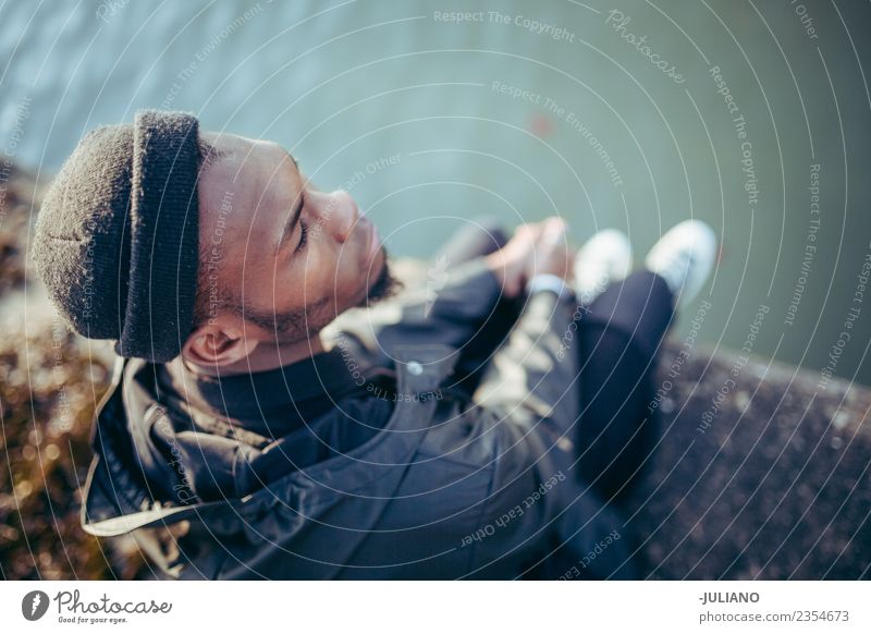 Junger Mann, der am Hafen sitzt und das Wasser hinunterschaut. Lifestyle Mensch Jugendliche 13-18 Jahre 18-30 Jahre Erwachsene Frühling schlechtes Wetter Wind