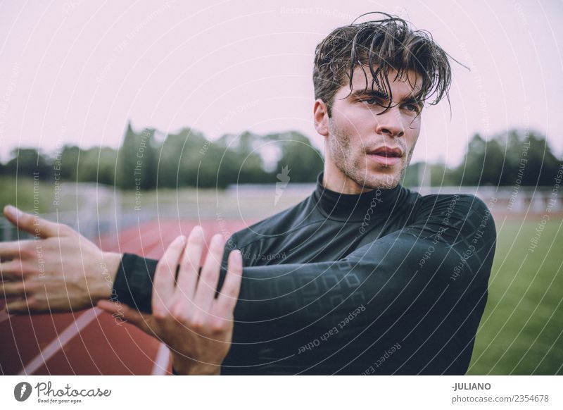 Junger Sportler macht Stretching auf der Laufbahn. Trinkwasser Lifestyle Freude Körper Gesundheit Gesunde Ernährung Gesundheitswesen sportlich muskulös Fitness